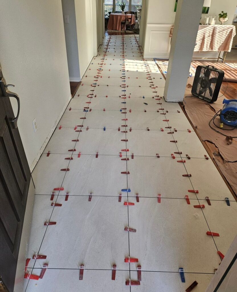 Ongoing floor tiling with spacers in a hallway